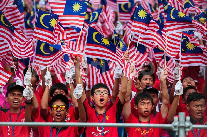 Group-Of-Malaysian-People-Waving-Flags-During-Malaysia-Day-Celebration.jpg